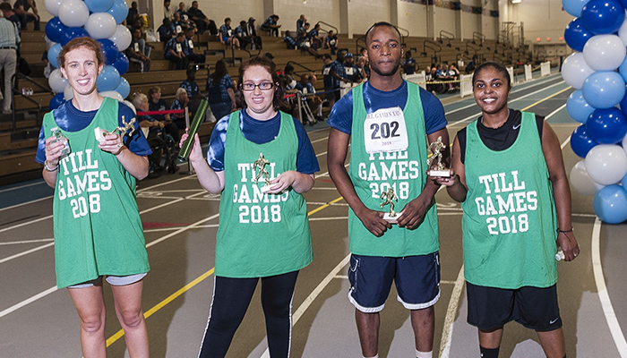 Four athletes standing in line smiling after race