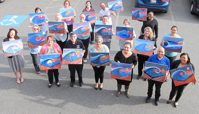 Art Class, 2 rows of artists holding up their paintings